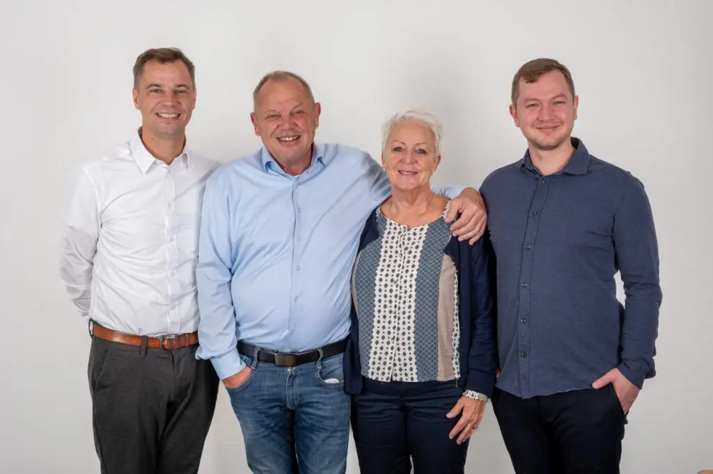 Fire medarbejdere fra Behrens Logistik står smilende sammen foran en hvid baggrund.