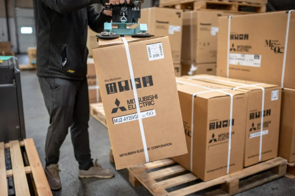 Medarbejder hos Behrens Logistik bruger vakuumløfter til at håndtere papkasse med Mitsubishi Electric produkt.