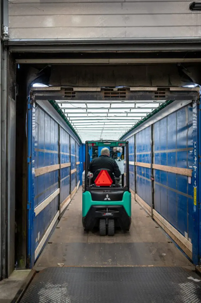 En gaffeltruck kører ind i en lagerhal hos Behrens Logistik, klar til at håndtere gods.