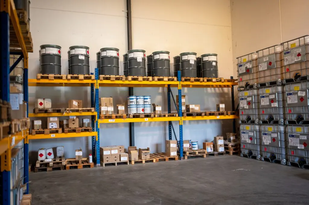 Tønder, dunke og IBC-containere med faremærkater opbevaret på lagerreoler.