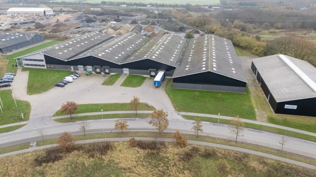 Luftfoto af moderne lagerbygninger tilhørende Behrens Logistik med lastbiler og biler.